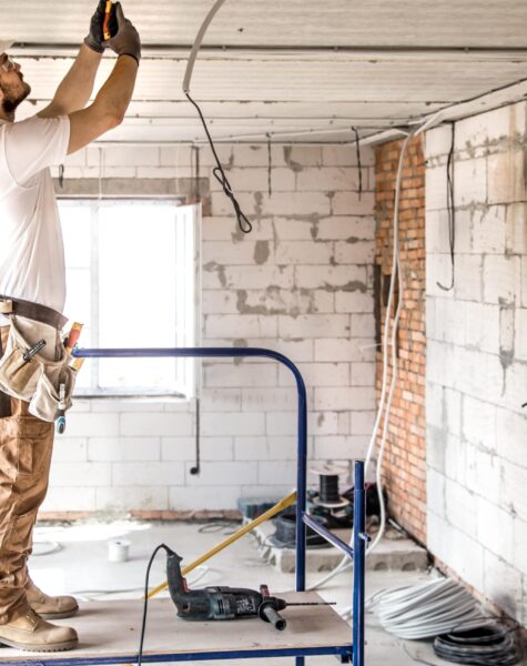 electrician-installer-with-tool-his-hands-working-with-cable-construction-site-min